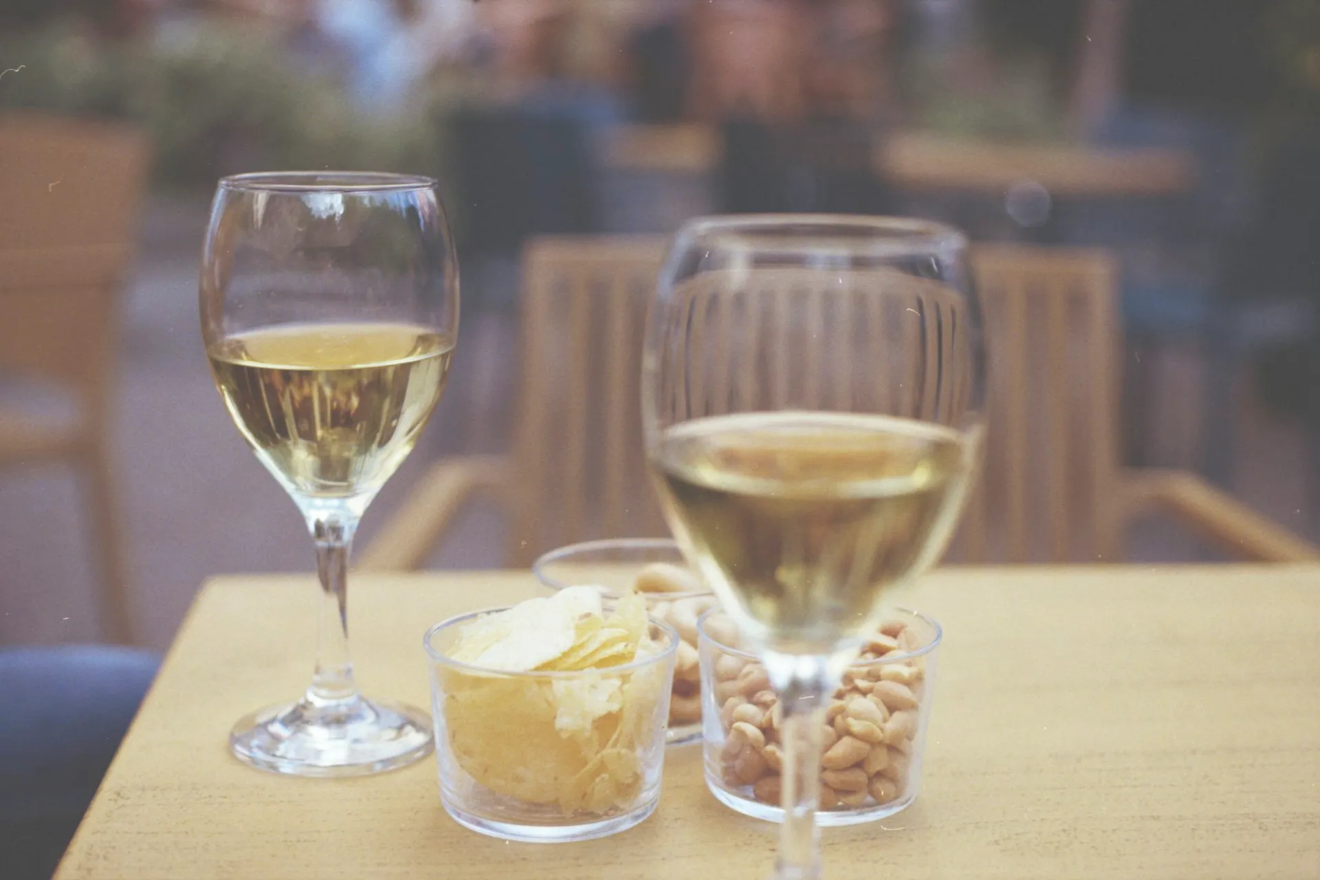 To glas hvidvin og snacks på et bord